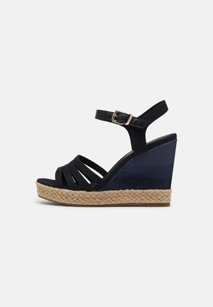 Sort kile-sandal med ankelrem, guldlås, flettet jutesål og tekstureret navyblå kilehæle.
