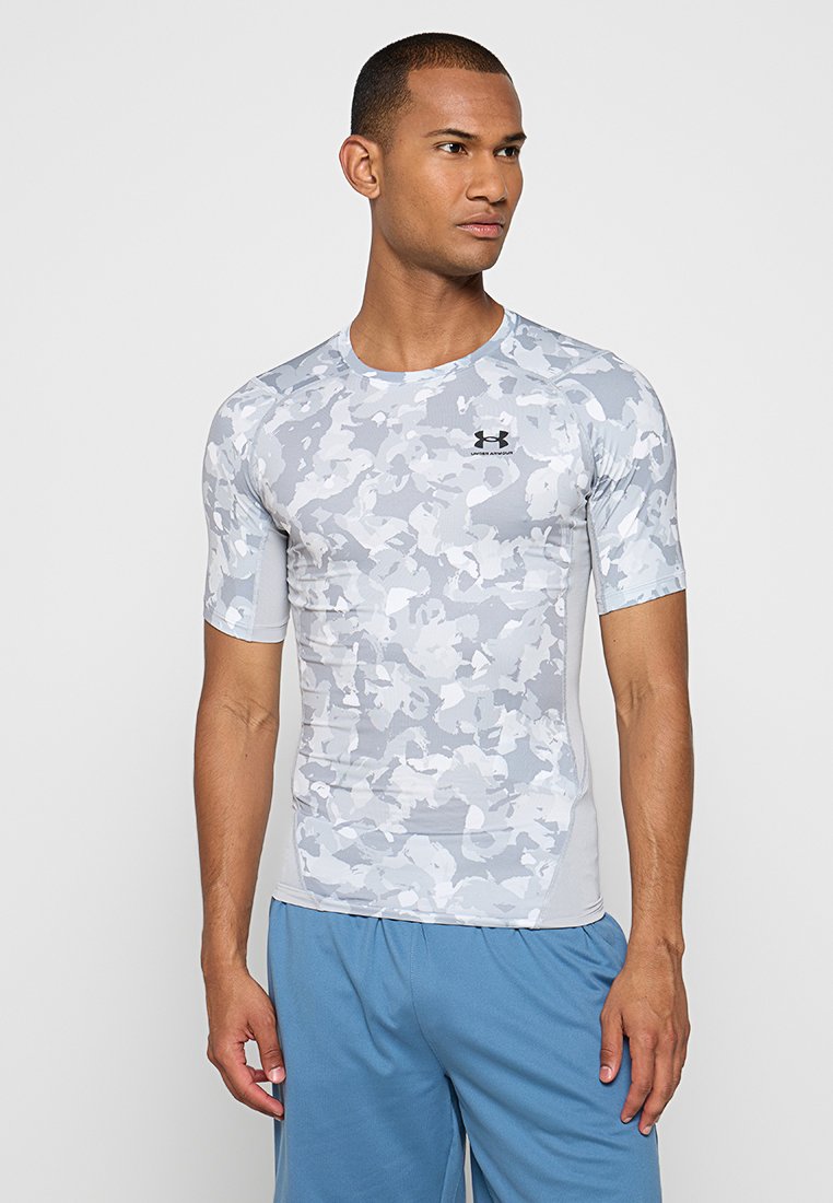 Camiseta atlética de manga corta en camuflaje gris, fabricada con material elástico, que cuenta con un cuello redondo y un logo en el lado izquierdo del pecho.