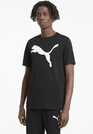 Čierne bavlnené tričko s veľkým bielym logom Puma, okrúhly výstrih, krátke rukávy a voľný strih. V páre s čiernymi nohavicami.