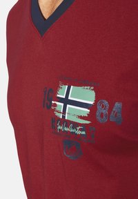 Red v-neck t-shirt made of cotton. Features a graphic with a green Norwegian flag, text in dark blue, and a distressed look.
