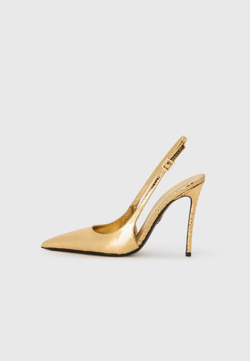 Zapatos de tacón dorados con punta afilada, que presentan un patrón de reptil texturizado, un alto tacón de aguja y un diseño de corte lateral abierto.