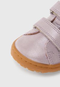 Chaussure métallique violette avec des bandes Velcro et une semelle en caoutchouc. Présente un bout arrondi et une surface supérieure texturée. Le design inclut des détails de couture.