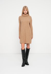 Gebreide jurk in een camel kleur met een hoge col en lange mouwen, met een ontspannen pasvorm die boven de knie valt.