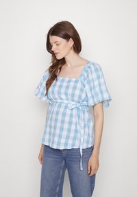Blusa azul clara e branca com padrões de xadrez, decote quadrado, mangas curtas e um laço na cintura, feita de um tecido texturizado.