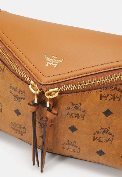 Brun läderkuvertväska med präglad MCM-logotyp och diamantram, guldfärgad dragkedjeutrustning och bruna detaljer på dragkedjesnoddarna.