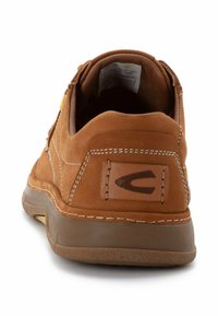 Brune ruskindssko med afrundet bag, syede detaljer, en tan farvet indersål og et logo patch på hælen. Gummisål med greb tekstur.