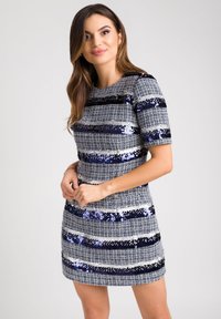 Sukienka z krótkim rękawem o dopasowanym kroju, wykonana z tkaniny tkanej z poziomymi paskami z niebieskich cekinów i metalicznych nici.