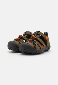 Grønne og svarte sandaler med oransje detaljer, med justerbare stropper, åpen tå-design og teksturerte gummisåler for grep.