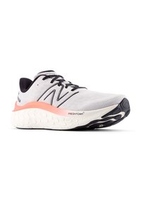 Zapatilla de running ligera con una parte superior de punto gris, acentos negros y una suela de espuma blanca con detalles en rosa. Diseño flexible y acolchado.