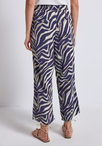 Wide-leg pants feature a purple and cream zebra print, made from lightweight fabric with a smooth texture. Elastic waistband and back pockets.