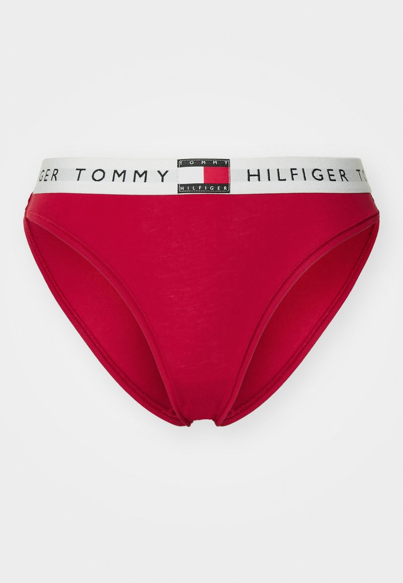 Slip rossi Tommy Hilfiger con un elastico bianco che presenta il nome e il logo del marchio in nero, bianco e rosso.