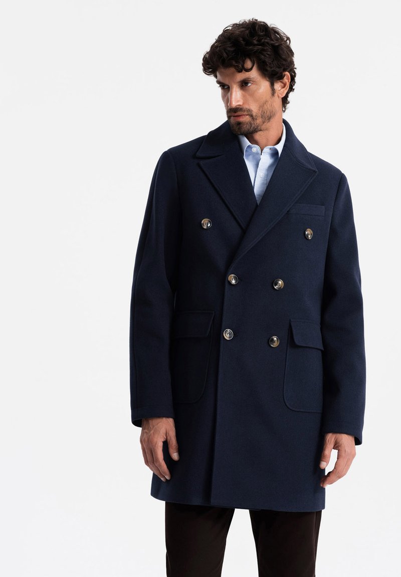 Cappotto doppiopetto in lana navy con due tasche frontali e bottoni argentati, con rever a punte e una silhouette strutturata.