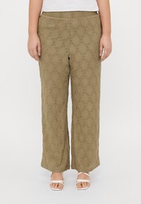 Λαδί παντελόνι σε ίσιο σχέδιο με υφή διαμαντιού και αφρώδες σχέδιο στο τελείωμα, συνδυασμένο με λευκές σαμπό με λουράκια.