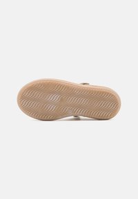 Suela de sandalia, de caucho marrón con un patrón de olas texturizado, que cuenta con una ligera elevación y bordes redondeados para ofrecer agarre y comodidad.