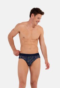 Herren-Bikini-Brief in Marineblau mit mehrfarbigen Handabdrücken. Weicher Stoff, elastischer Bund mit Markenlogo, figurbetontes Design und moderate Abdeckung.