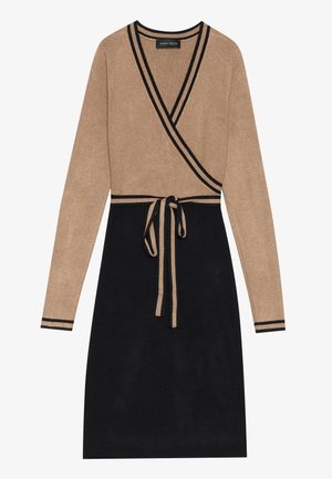 Vestido envolvente de parte superior beige y falda negra. Mangas largas con rayas negras, detalle de cinta en la cintura, textura acanalada en toda la prenda.