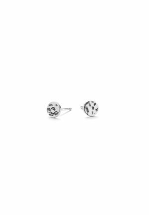Paire de boucles d'oreilles rondes en argent avec un motif irrégulier tacheté de noir sur fond blanc.