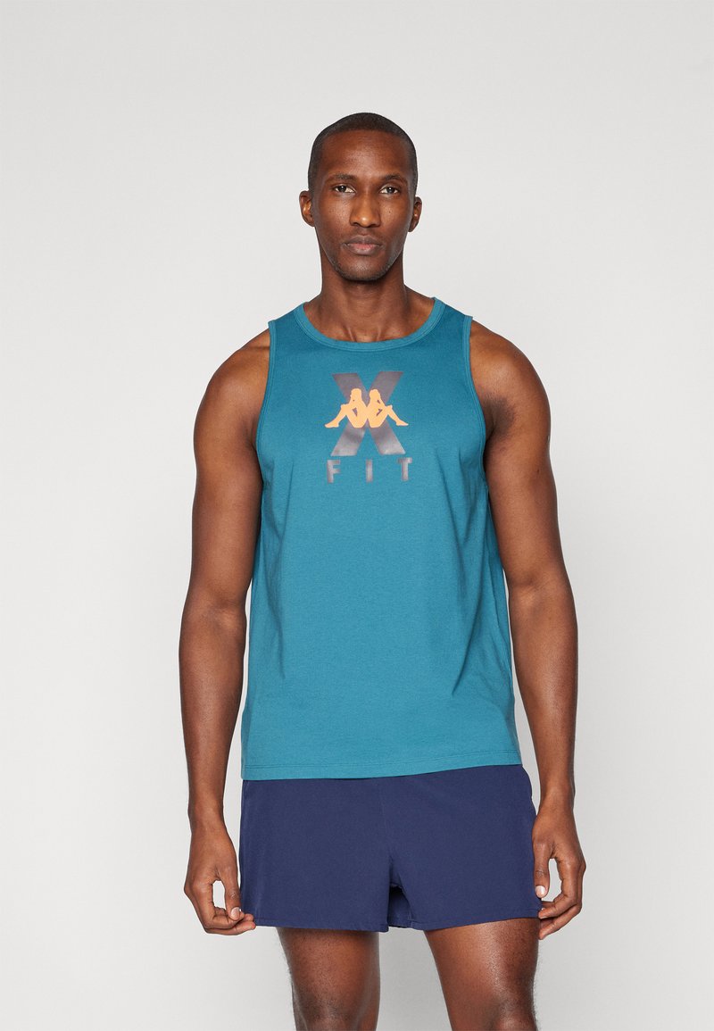 Teal ermeløs tanktop med oransje grafisk tekst "X FIT" og logo på forsiden, laget av lett stoff. Kombinert med marineblå shorts.