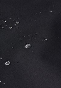Waterdichte zwarte stof met een gestructureerd oppervlak, met verspreide waterdruppels van verschillende groottes over het materiaal.