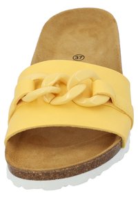 Gelbe Rutschsandale mit glänzendem Kettenakzent, strukturiertem Fußbett und Korkbasis. Die Sohle hat einen weißen Gummitrim. Angezeigte Größe: 37.