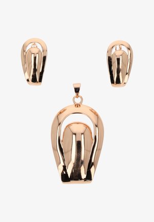 Aranyszínű fém fülbevalók és hozzáillő medál sima, ívelt absztrakt mintával és polírozott, tükröződő felülettel.