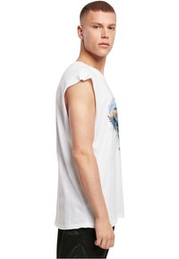 Weißes, ärmelloses T-Shirt aus Baumwolle mit Rundhalsausschnitt, mit einem grafischen Druck in Blau und Grau, seitlich an einem Modell präsentiert.