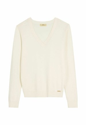 Kremowy sweter z dekoltem w serek, długimi rękawami, ściągaczami na mankietach i u dołu, o minimalistycznym wzorze oraz z małą złotą metką marki przy dole.