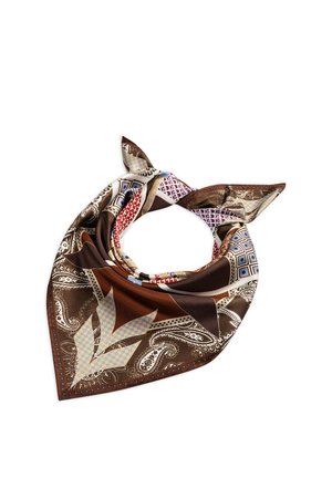 Square silk scarf with brown, beige, red, and blue geometric and paisley patterns, loosely folded with knot and pointed ends visible.