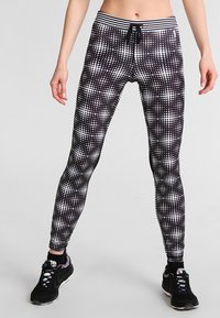Leggings a pois bianco e nero con un design aderente, dotati di una vita elastica e laccetto, realizzati in un materiale elasticizzato.