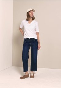 Hvid bomulds V-hals t-shirt, mørkeblå denim straight-leg jeans, beige cap og brune sneakers med cremefarvede snørebånd. En simpel og afslappet påklædning.