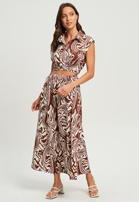 Ensemble deux pièces comprenant un crop top à motif tourbillon marron et crème avec un col et une jupe longue assortie, le tout en tissu léger.