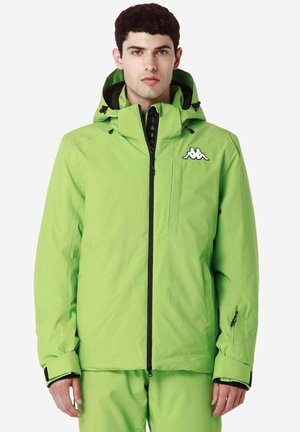 Giacca impermeabile verde con cappuccio, dettagli neri, chiusura con zip e logo sul petto. Presenta polsini regolabili e tasche.