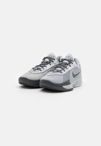 Jasnoszare buty sportowe z siateczkową cholewką, kontrastującymi ciemnoszarymi akcentami, teksturowaną podeszwą oraz wyraźnym logo Nike na boku.