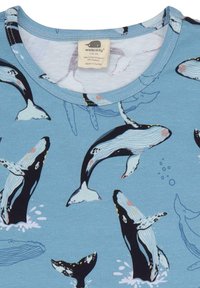 Helles blaues T-Shirt mit einem Muster von weißen und schwarzen Walen, umgeben von fließenden Linien und Blasen. Weicher Baumwollstoff mit rundem Halsausschnitt.