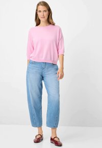 Maglione rosa a maniche corte in morbido tessuto lavorato a maglia abbinato a jeans azzurri a gamba larga e ballerine bordeaux con dettaglio fibbia dorata.