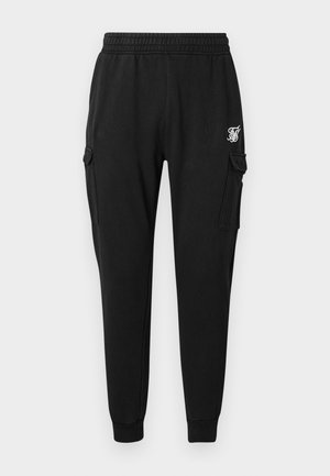 Black cargo pants made from soft fabric featuring an elastic waistband, side pockets, and a discreet logo on the thigh. Straight cut design.
