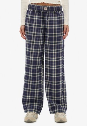 Marineblå og hvide ternede bukser med vide ben, elastisk talje og knapdetalje, båret med beige sneakers og en kort hvid langærmet top.