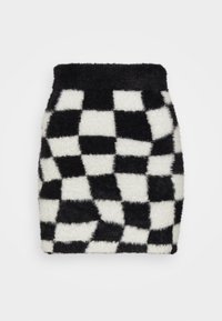 Jupe mini damier noir et blanc en matériau doux et moelleux, avec une taille ajustée, présentant des carrés alternés dans un motif audacieux.