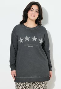 Felpa grigia a maniche lunghe con grafiche a forma di stella argentata e il testo "Dal 2006 Rimani Sempre Fedele" sotto. Polsini e orlo a costine.