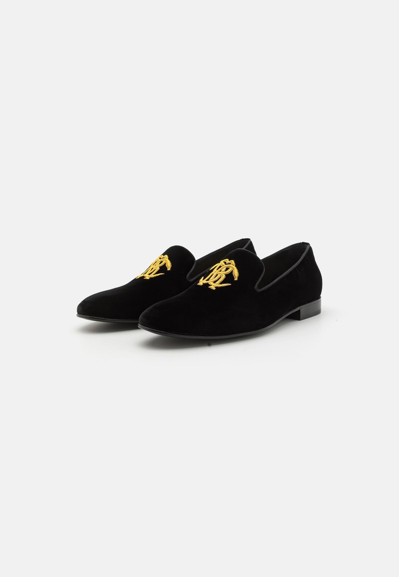 Mocasines de terciopelo negro con una forma elegante, que cuentan con un logo bordado en oro en la parte delantera. Textura suave y diseño de tacón minimalista.