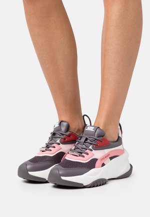 Chunky sneakers with mesh panels, dark purple, pink, and white synthetic materials, featuring a round toe, thick sole, and prominent branding.