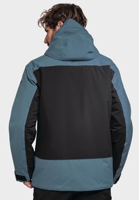 Wasserdichte Jacke mit schwarzem Körper und blauen Akzenten, ausgestattet mit einer Kapuze und strukturiertem Stoff. Verstellbare Bündchen und ein lockerer Schnitt.