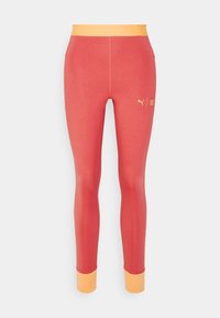Leggings rossi con un design aderente, con una vita arancione e polsini alla caviglia. Realizzati in materiale elastico con una consistenza liscia.