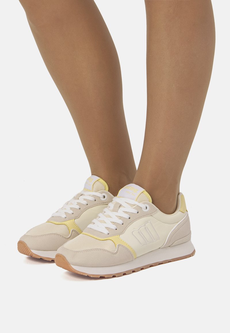 Scarpe da ginnastica beige e gialle con tomaia in mesh e camoscio, punta tonda, collo imbottito, lacci bianchi e suola in gomma.