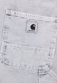 Heledan denim kangas heleshall hall. Üks rinnatasku. Taskul on tikitud must Carhartt logo silt.