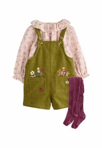 Grüne Cordoveralls mit Blumenstickerei, kombiniert mit einer rosa Bluse mit langen Ärmeln und Rüschensaum sowie bordeauxfarbenen gerippten Strumpfhosen.
