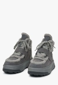 Szare sneakersy o futrzastej teksturze, z grubą podeszwą, regulowanymi paskami i kontrastującymi jaśniejszymi szarymi akcentami.