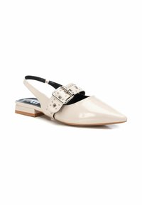 Zapato de charol beige tipo slingback con punta afilada, detalle de hebilla plateada y tachuelas. Tacón bajo y textura suave.