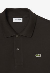 Tmavohnedé poloko s rebrovaným golierom, zapínaním na dve gombíky a zeleným vyšitým logom krokodíla Lacoste na hrudi.