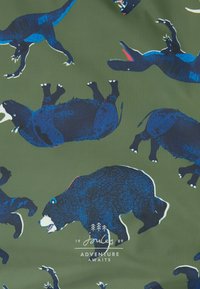 Tissu vert avec un motif répété d'animaux noirs et bleus, y compris des ours et des dinosaures, avec une texture lisse et un minimum de marques.
